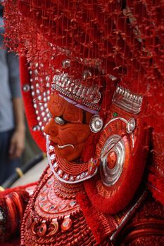 A close-up of a Theyyam performer adorned in intricate traditional costume and makeup.