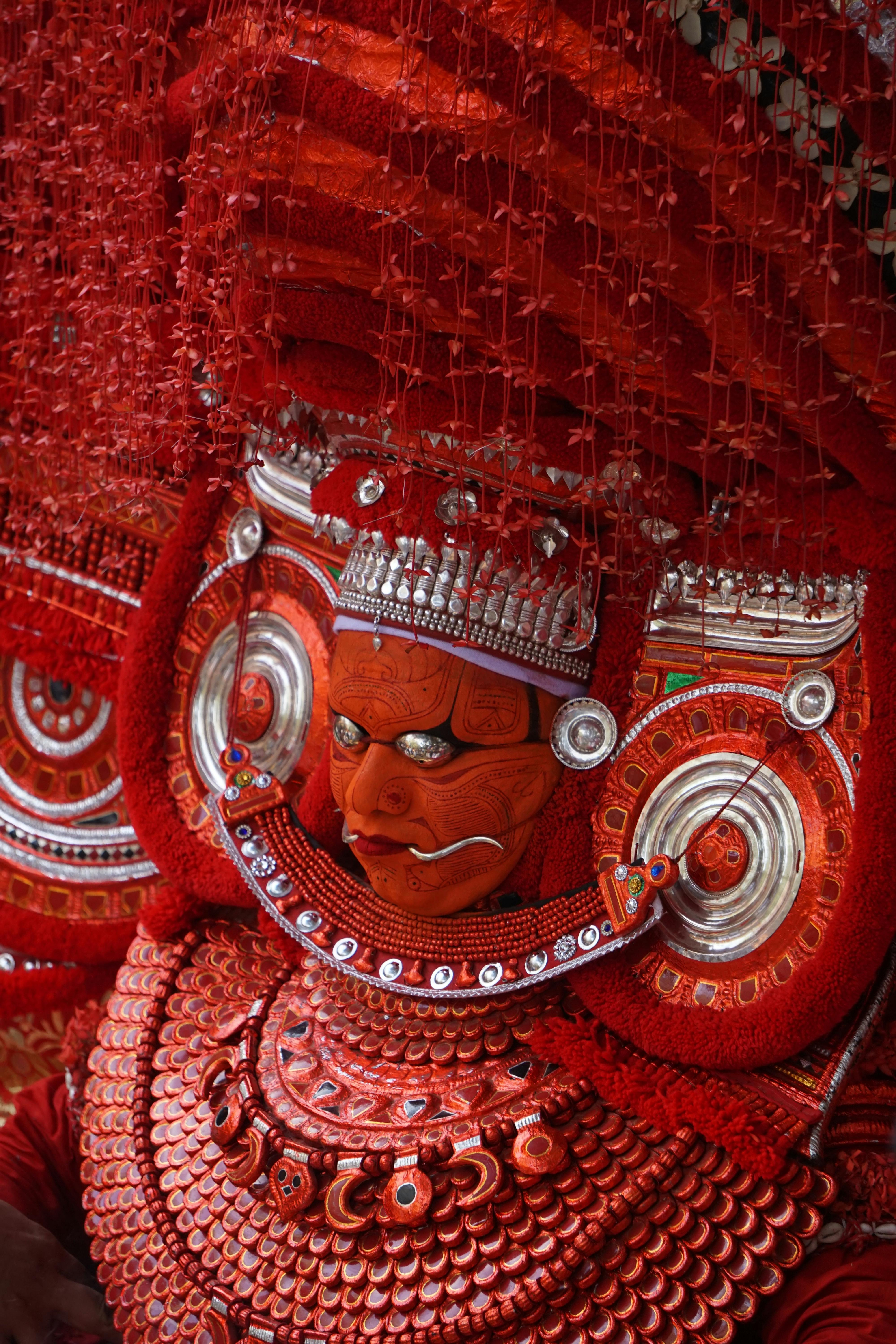 common:alt.prefix Nahaufnahme eines traditionellen Theyyam-Künstlers in einem aufwendigen roten Kostüm in Kerala, Indien. common:alt.postfix