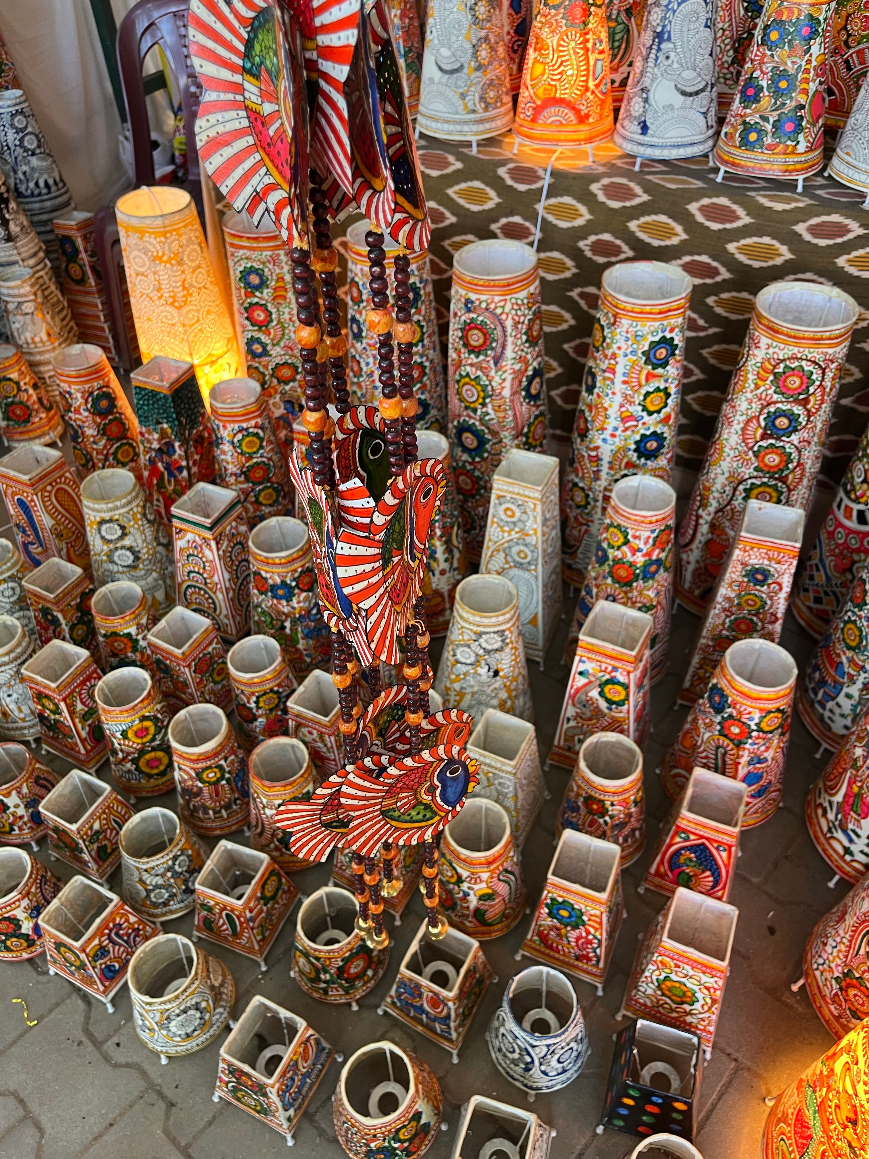Vibrant display of handcrafted ceramic vases and lamps with intricate patterns at an artisan market.