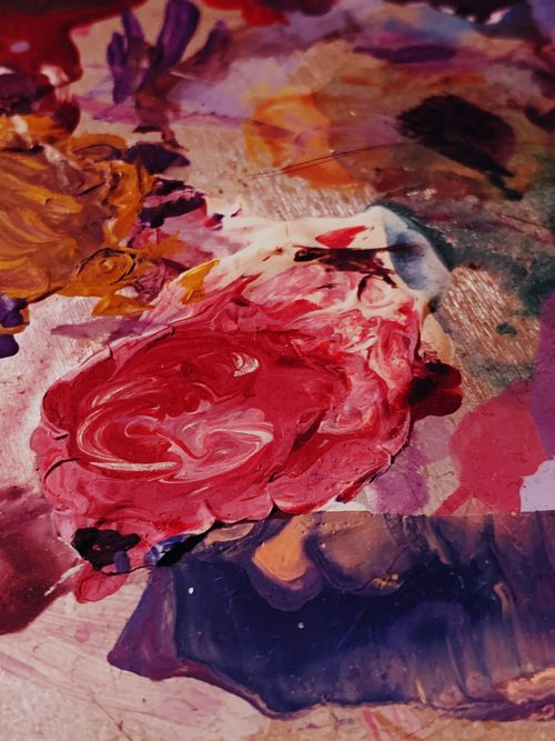 Free Close-up of a vibrant abstract painting featuring swirling acrylic colors on a messy palette. Stock Photo