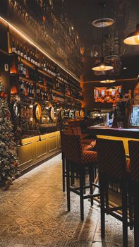 A warmly lit bar with vintage decor and stocked wine shelves, exuding a cozy atmosphere.