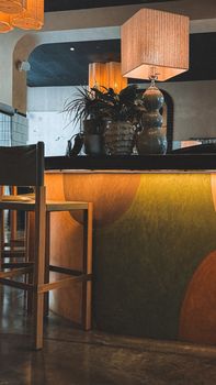 A modern bar interior with stylish lighting, plants, and retro decor elements.
