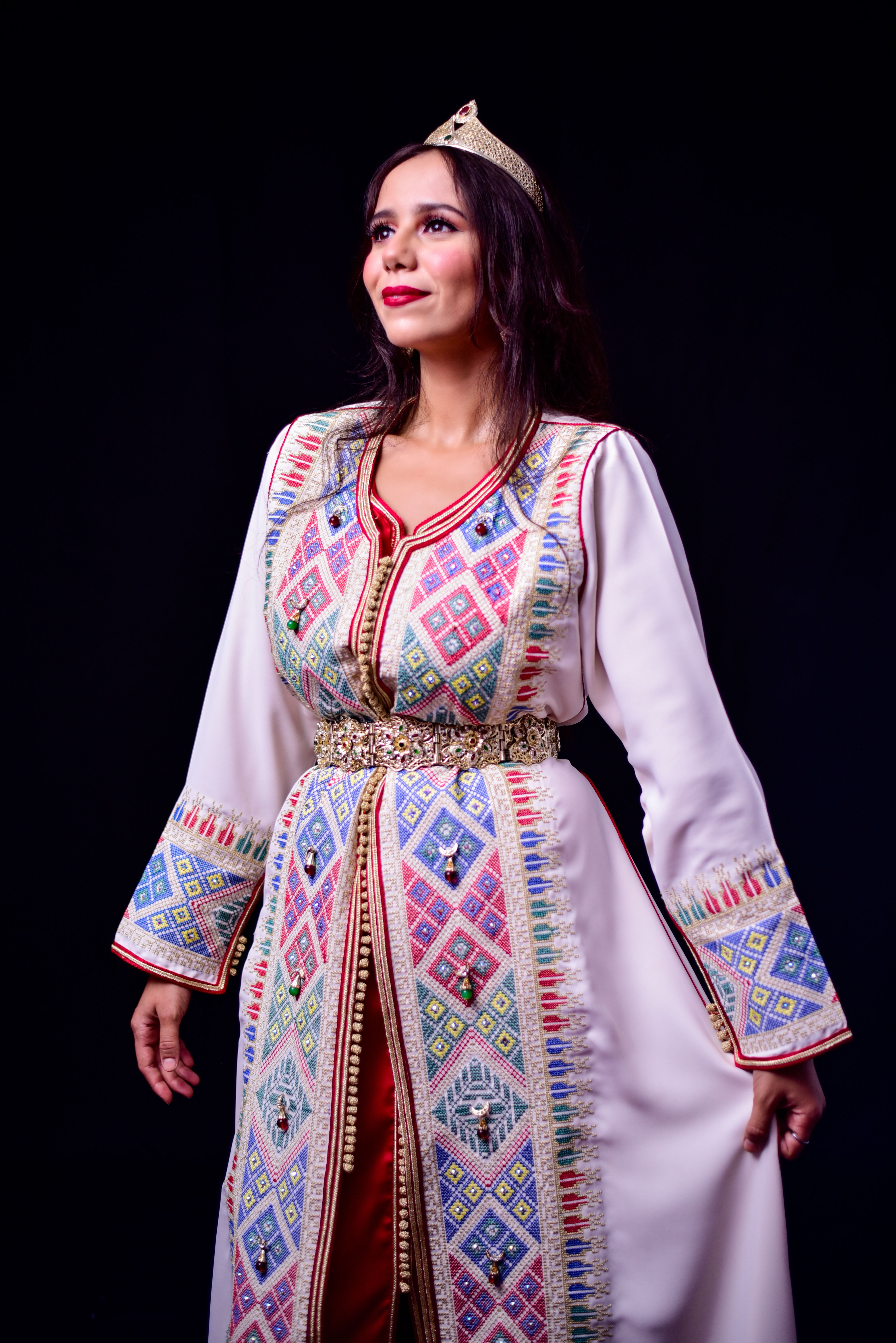 Portrait of a woman in elaborate Moroccan attire with intricate patterns.