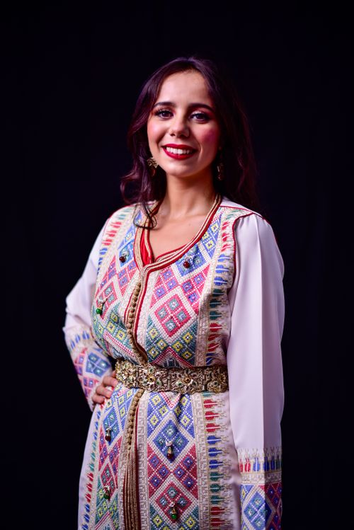 Free Portrait of a smiling woman in a colorful traditional Moroccan dress with intricate patterns. Stock Photo