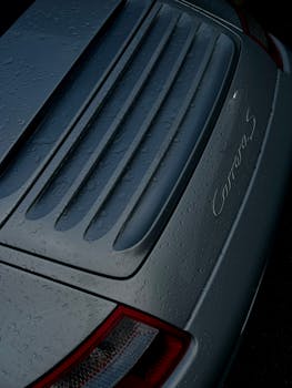 Detailed view of a sports car rear with raindrops, showcasing its luxury design.