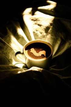 A warm cup of coffee on a bed illuminated by morning sunlight, creating a cozy atmosphere.