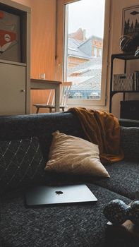 A cozy living room setting with a laptop, cushions, and soft lighting, perfect for relaxation.