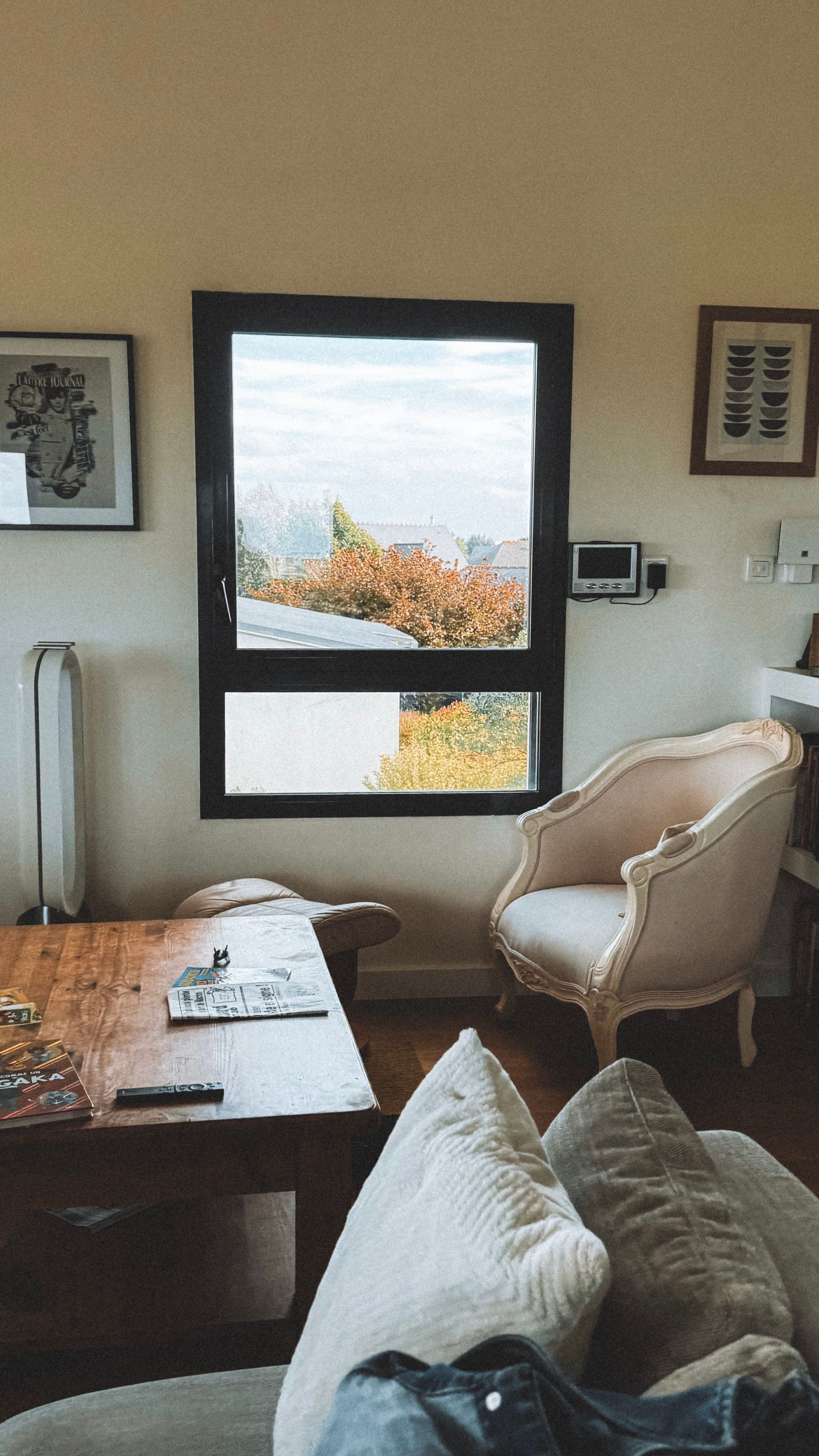 Calm living-room chair facing large windows with warm autumn foliage outside
