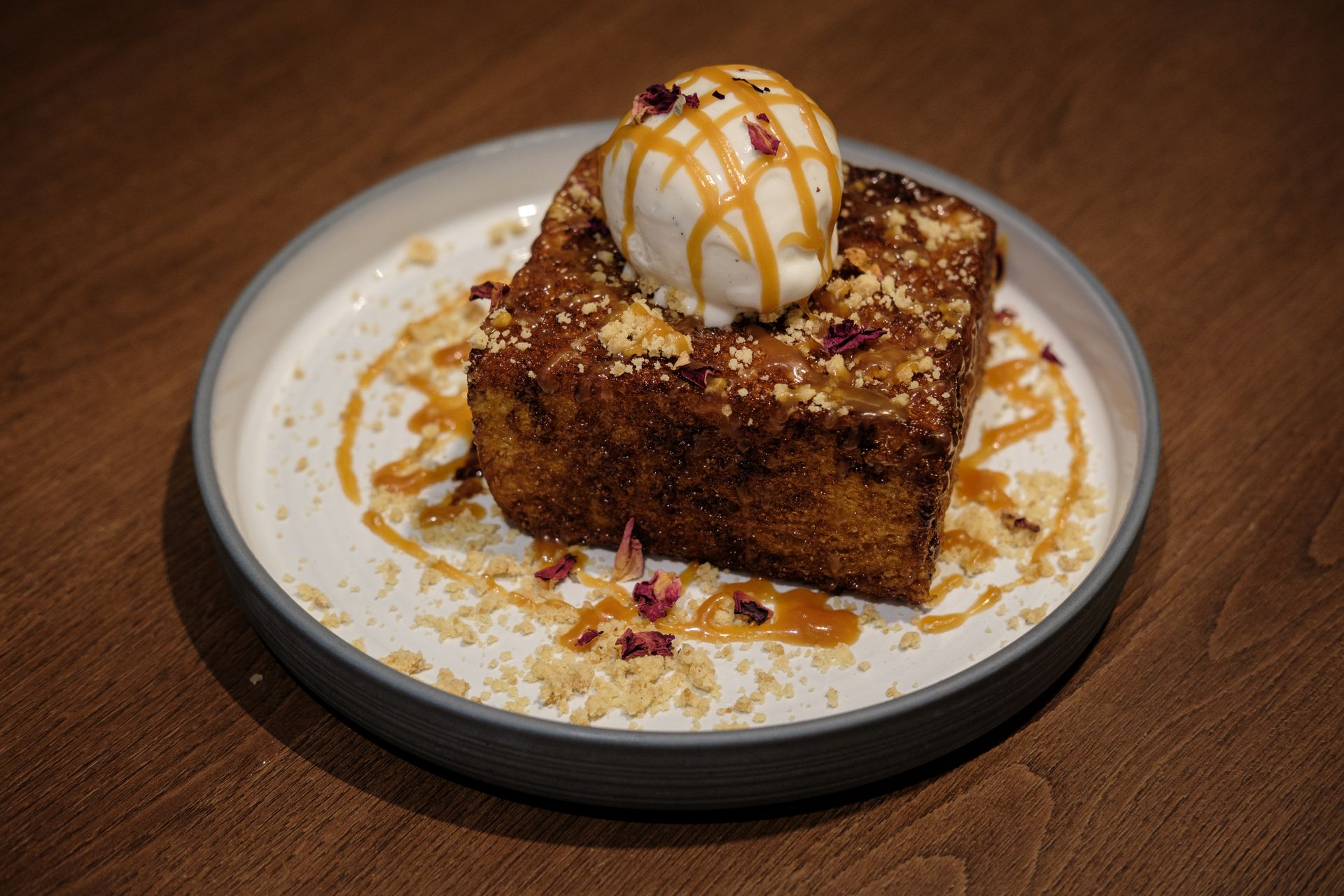 Mouthwatering French toast topped with ice cream and caramel, garnished with rose petals and crumbles in Mumbai.