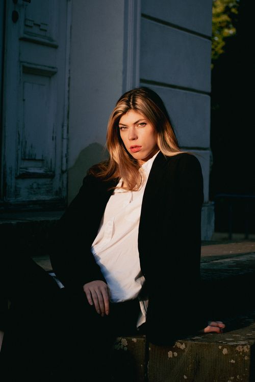 Free Elegant woman posing outdoors in natural light, wearing a black jacket. Captivating portrait showcasing beauty and style. Stock Photo