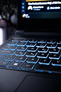 Close-up of a modern gaming laptop keyboard with blue backlit keys, suitable for tech and lifestyle themes.