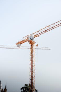 A tall yellow tower crane set against a clear blue sky, ideal for construction themes.