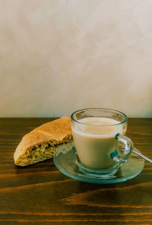 Free A classic Moroccan breakfast setup featuring a glass of milk coffee and traditional bread on a rustic table. Stock Photo