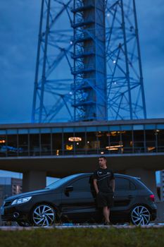 Urban scene featuring man with car and architecture in Brasília during twilight.