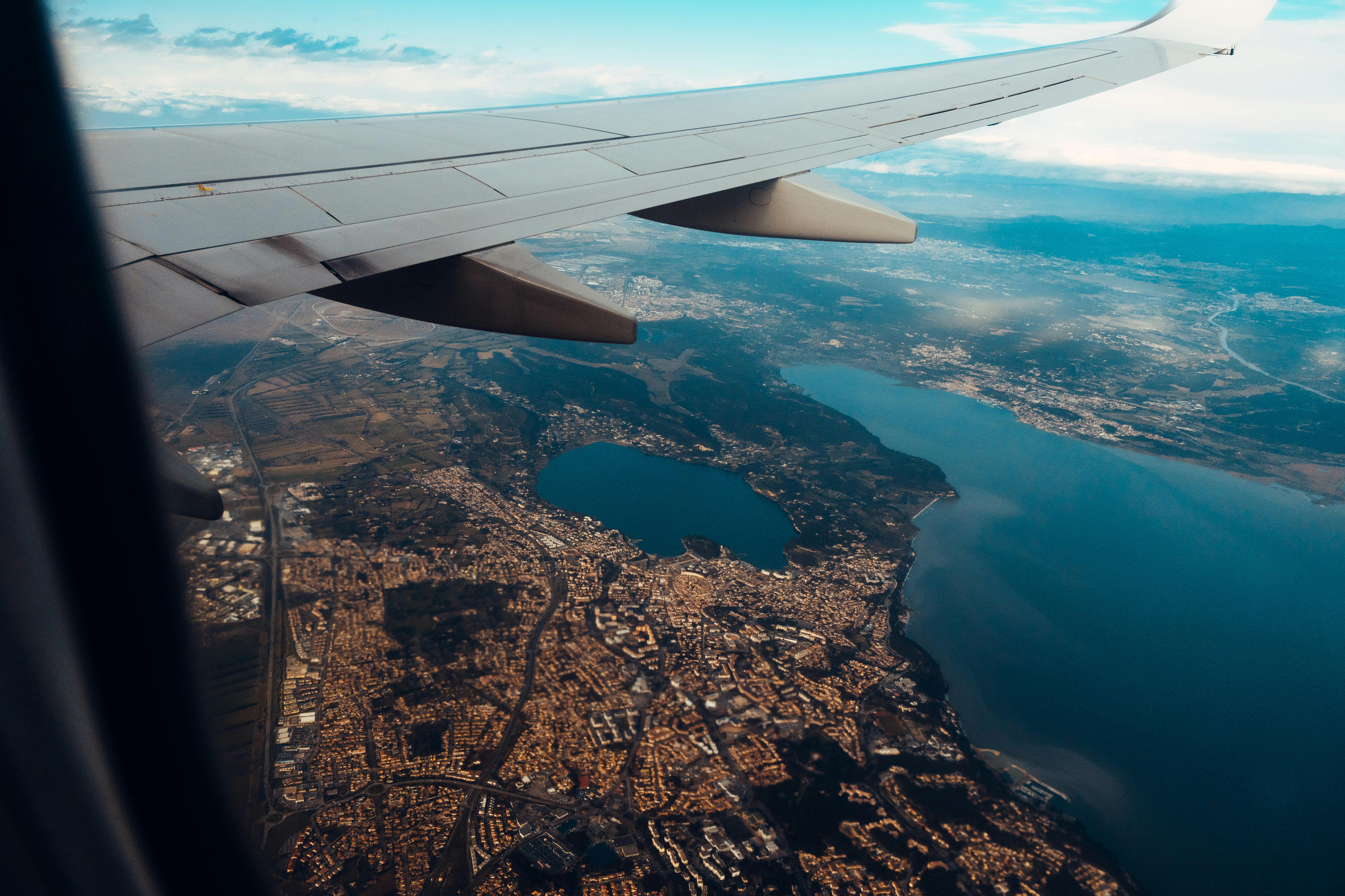 A stunning aerial view from an airplane window showing a coastline and cityscape below.