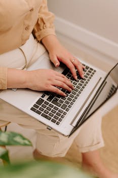 A woman typing on a laptop indoors, embodying a productive work-from-home environment.