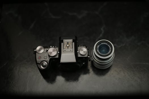 Un corpo macchina fotografica e un obiettivo esposti su una superficie di marmo scuro, per mettere in risalto l'attrezzatura fotografica.