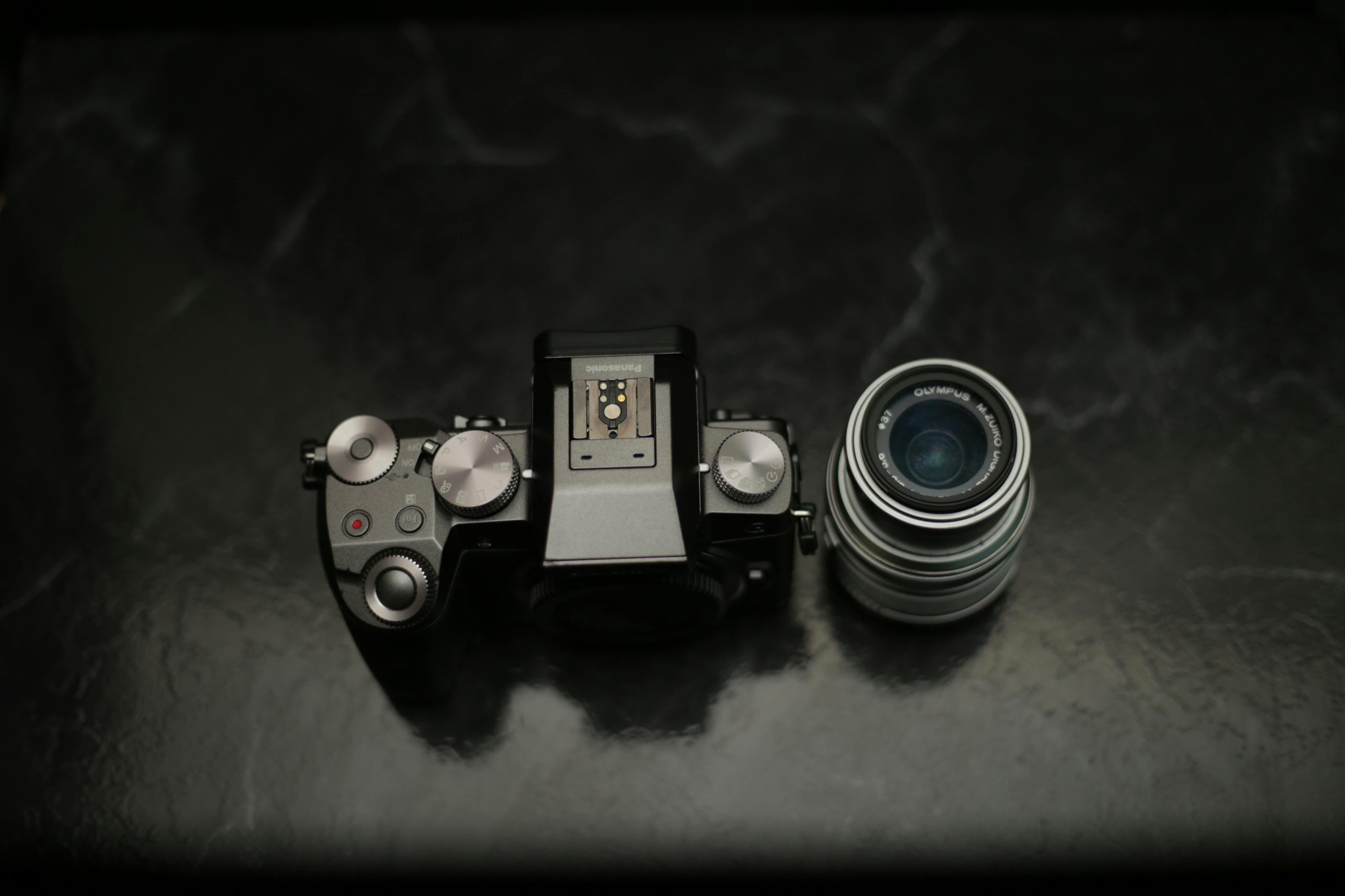 gratis Een camerabody en lens tentoongesteld op een donker marmeren oppervlak, met de nadruk op fotografische apparatuur. Stockfoto