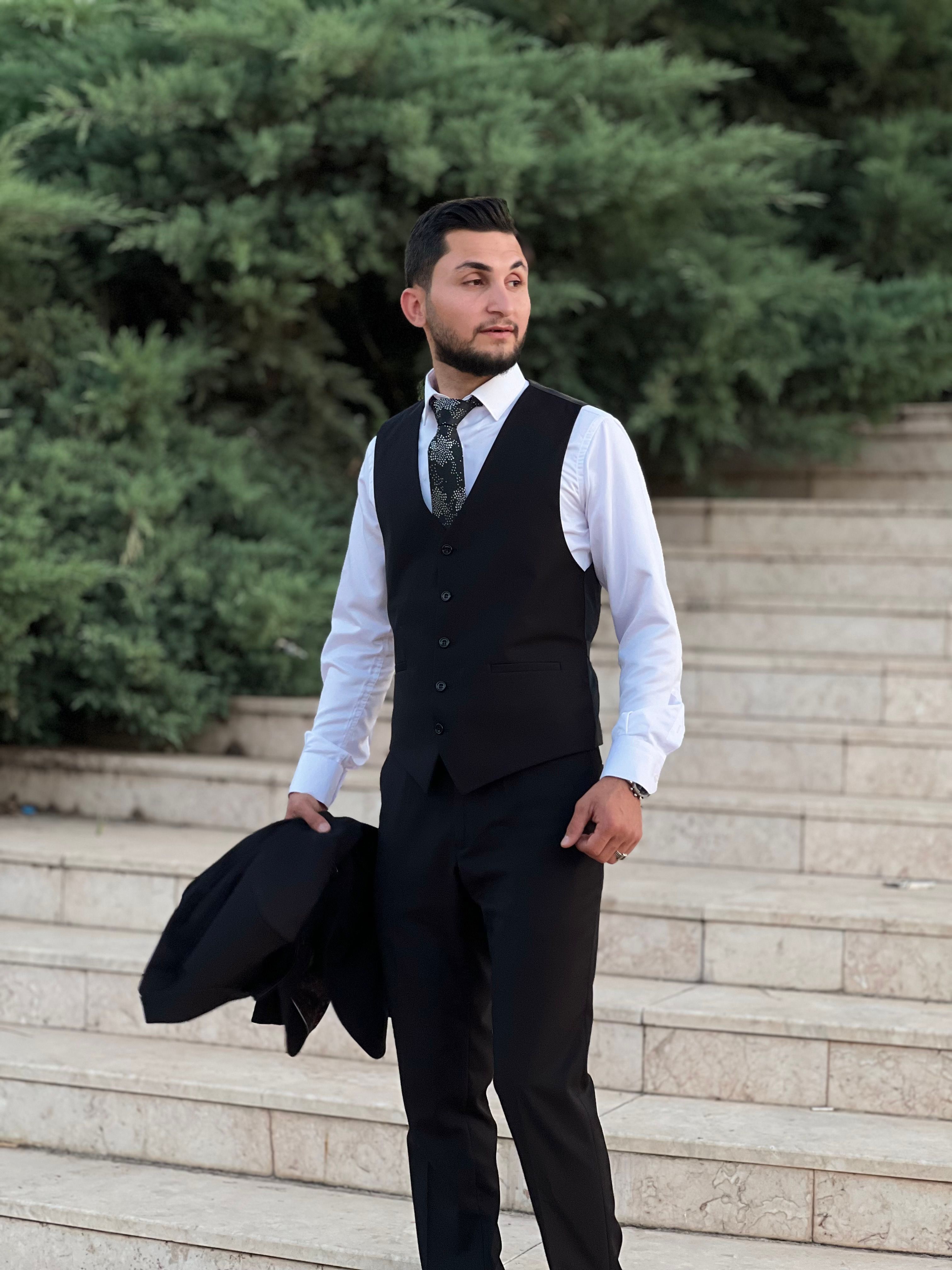 Young man in elegant suit holding jacket confidently on outdoor stone steps.