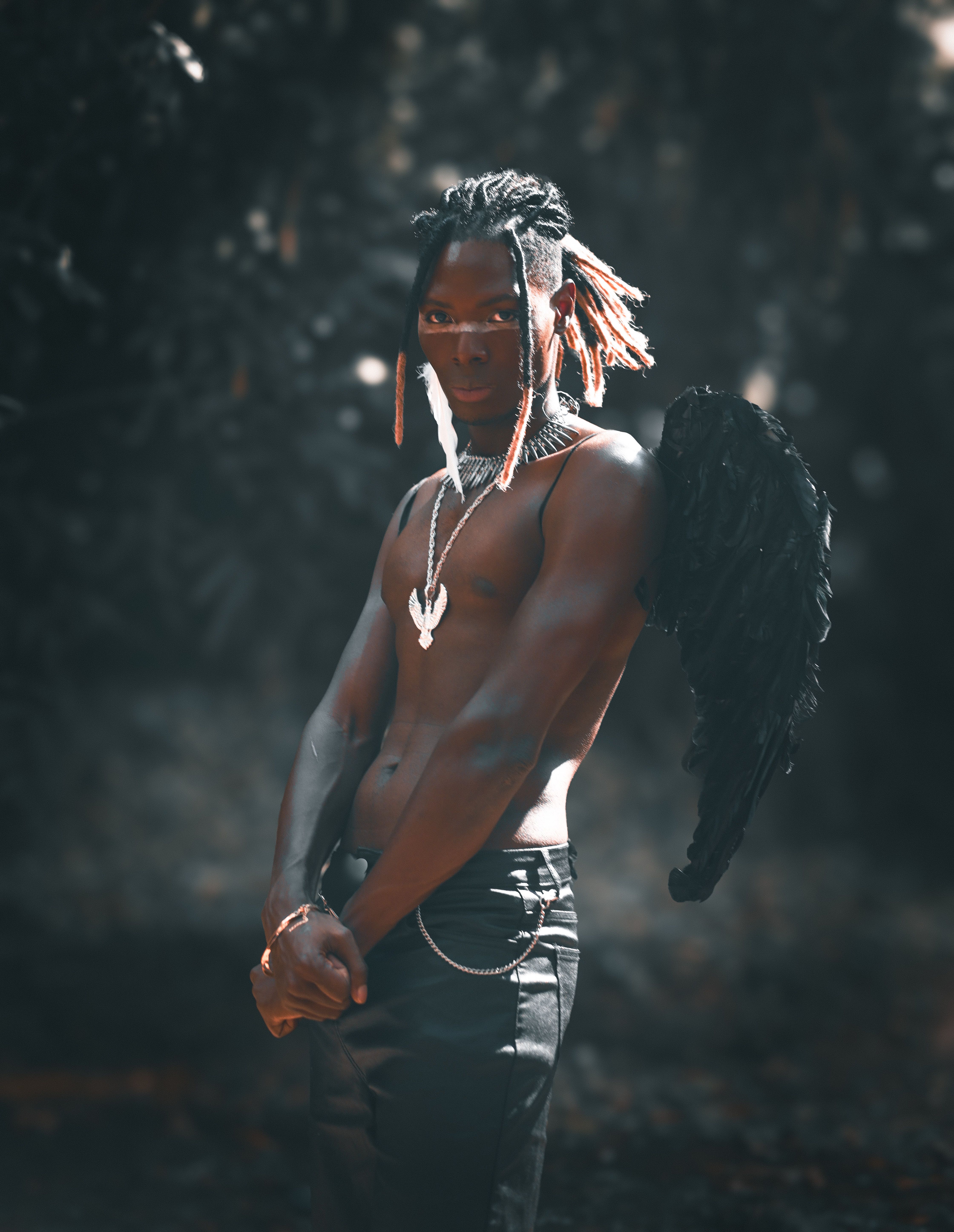 A powerful portrait of a man wearing angel wings in a dimly lit outdoor setting.