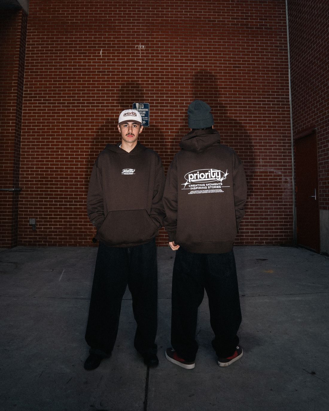 Personas con sudaderas streetwear frente a una pared de ladrillo