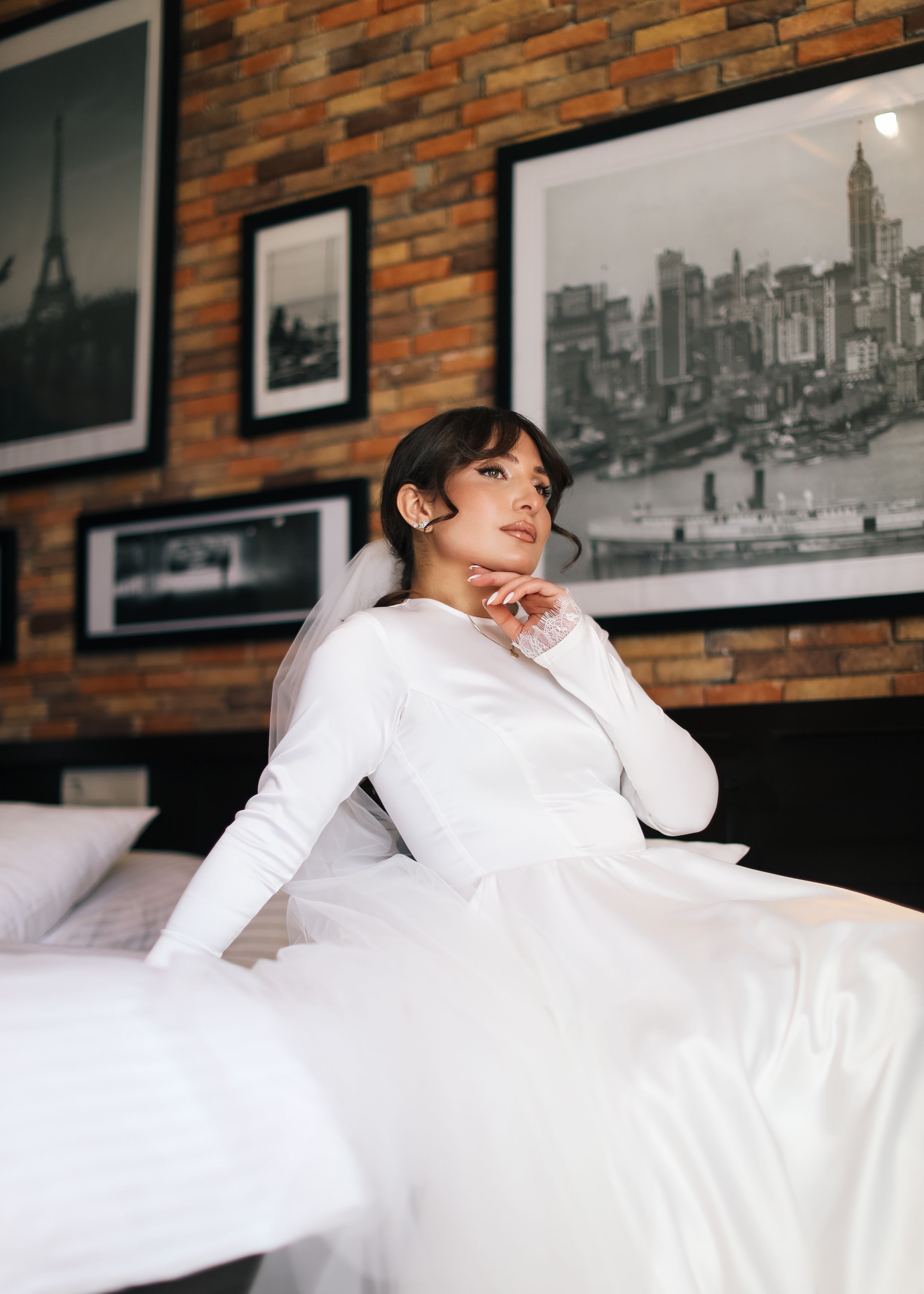 Bride in white gown in front of modern art, surrounded by urban framed pictures.