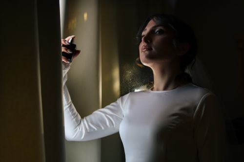 Free Elegant bride using perfume bottle, highlighted by moody lighting indoors. Stock Photo