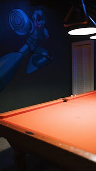 An indoor pool table beneath elegant lighting and robot-themed mural.
