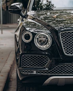 Close-up of a black luxury car showcasing its sleek, reflective surface and elegant design.