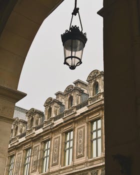 Elegant view of historic Parisian architecture through an archway, featuring a classic street lamp.