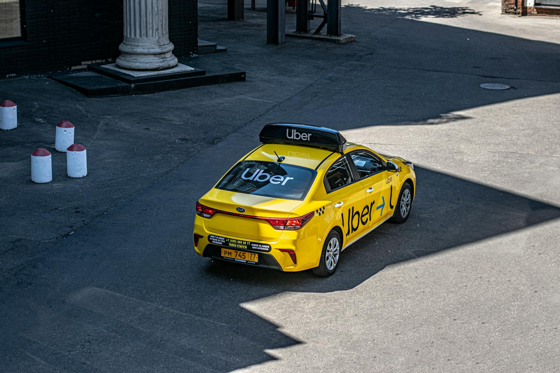 A yellow Uber taxi driving on a city street, shown from above.