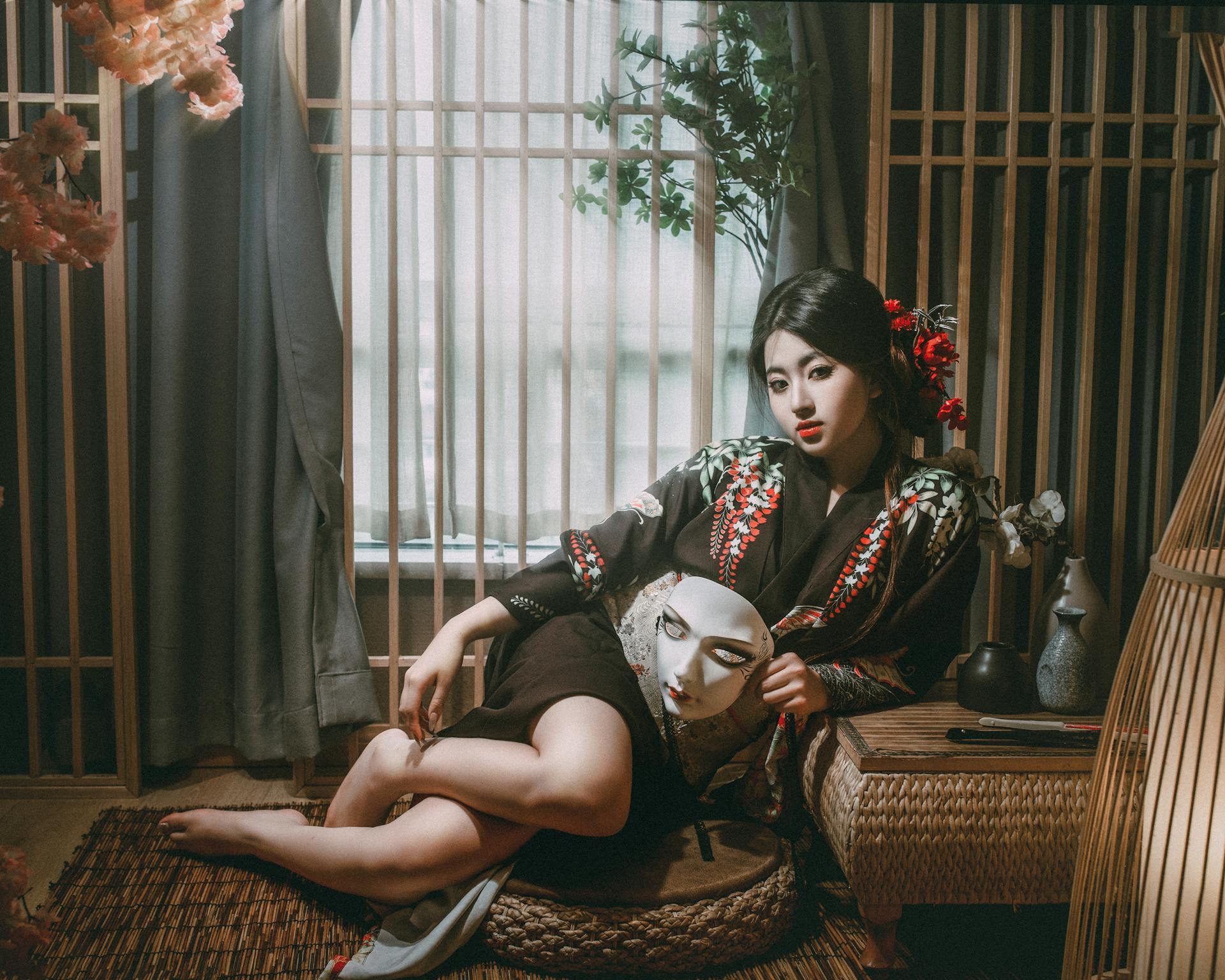 Beautiful woman in a kimono holds a mask in a traditional Japanese setting, evoking mystery and elegance.
