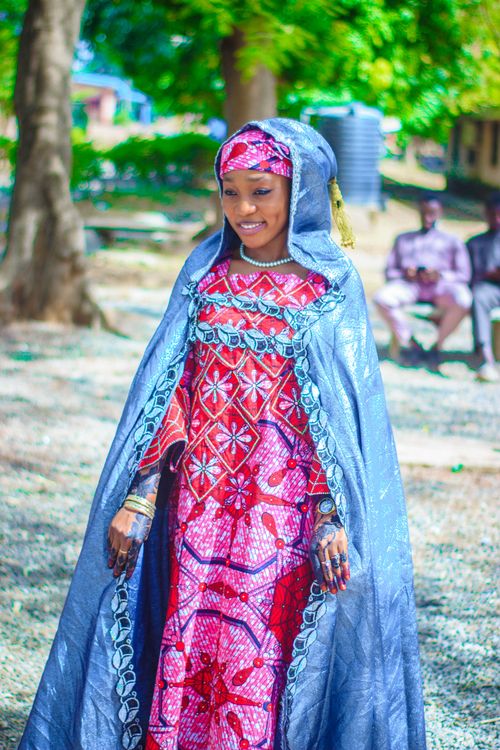 Free A woman in vibrant traditional African attire smiling outdoors, embodying cultural elegance. Stock Photo