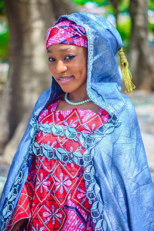 Free A woman in vibrant traditional clothing and headscarf, smiling outdoors. Stock Photo
