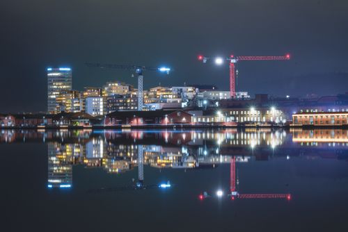 Free Beautiful night cityscape reflecting in water with urban lights and cranes in Jönköping, Sweden. Stock Photo