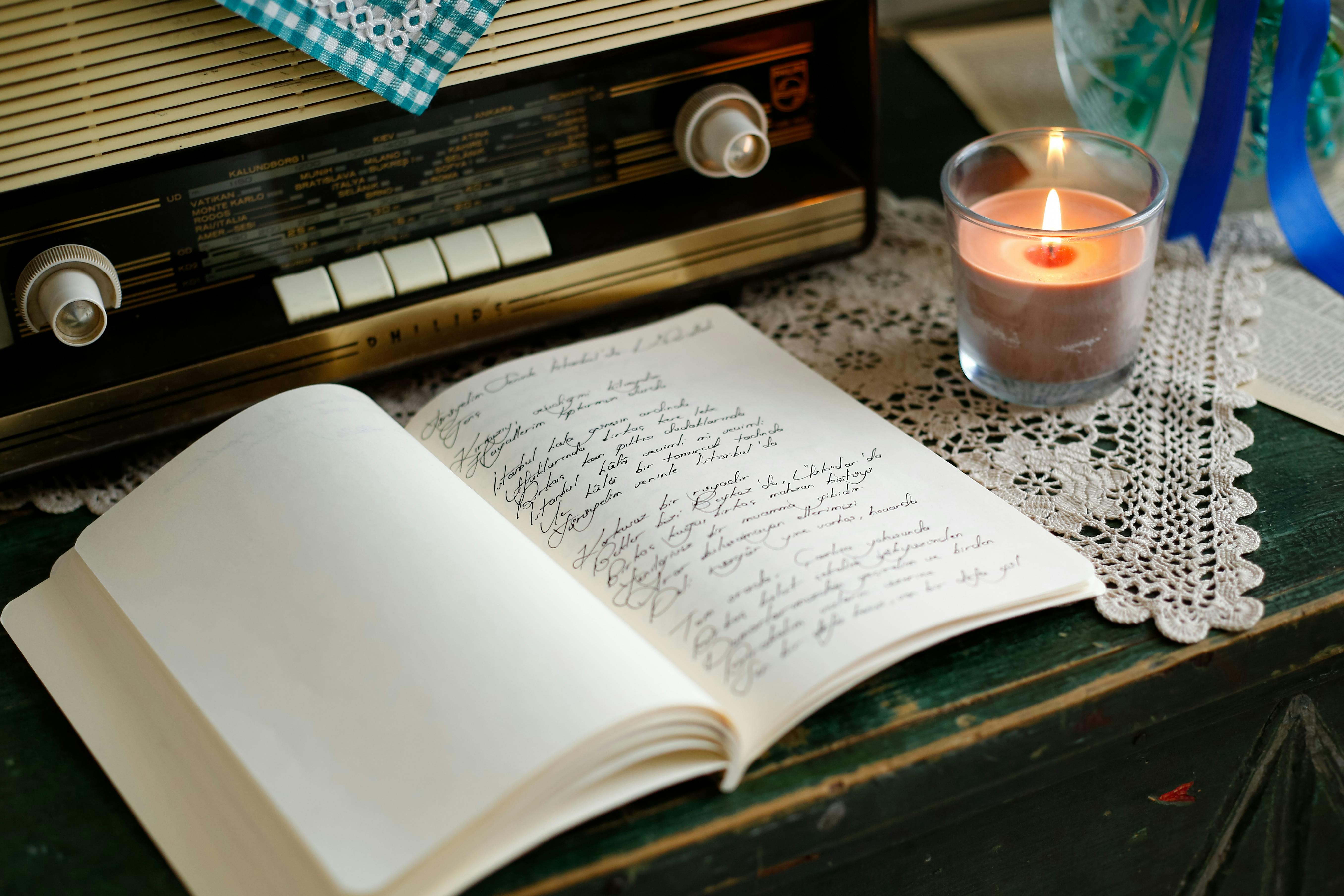 Cozy vintage setting with an old radio, handwritten notes, and a lit candle on crocheted lace.