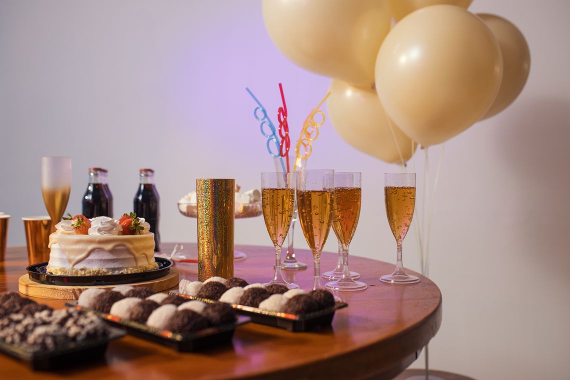 Festive celebration table with balloons, cake, drinks, desserts, and elegant party styling