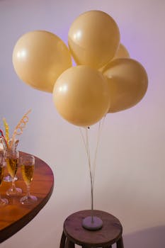 Stylish birthday party setup featuring golden balloons and champagne glasses on a wooden table.