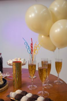 A festive Brazilian party setup with champagne glasses and golden balloons for a sophisticated celebration.