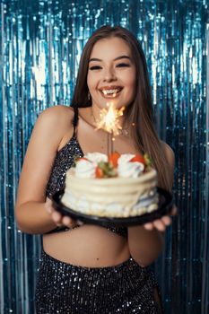Joyful Brazilian birthday celebration with a smiling woman holding a cake with a sparkler.