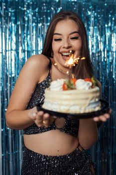 A woman celebrating her birthday with a cake topped with sparklers, exuding happiness and festive vibes.