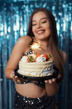 A festive birthday celebration in Brazil featuring a cake with a sparkling candle held by a smiling young woman.