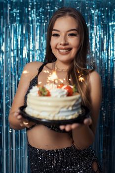 Smiling woman holding a cake with sparklers at a Brazilian birthday party.
