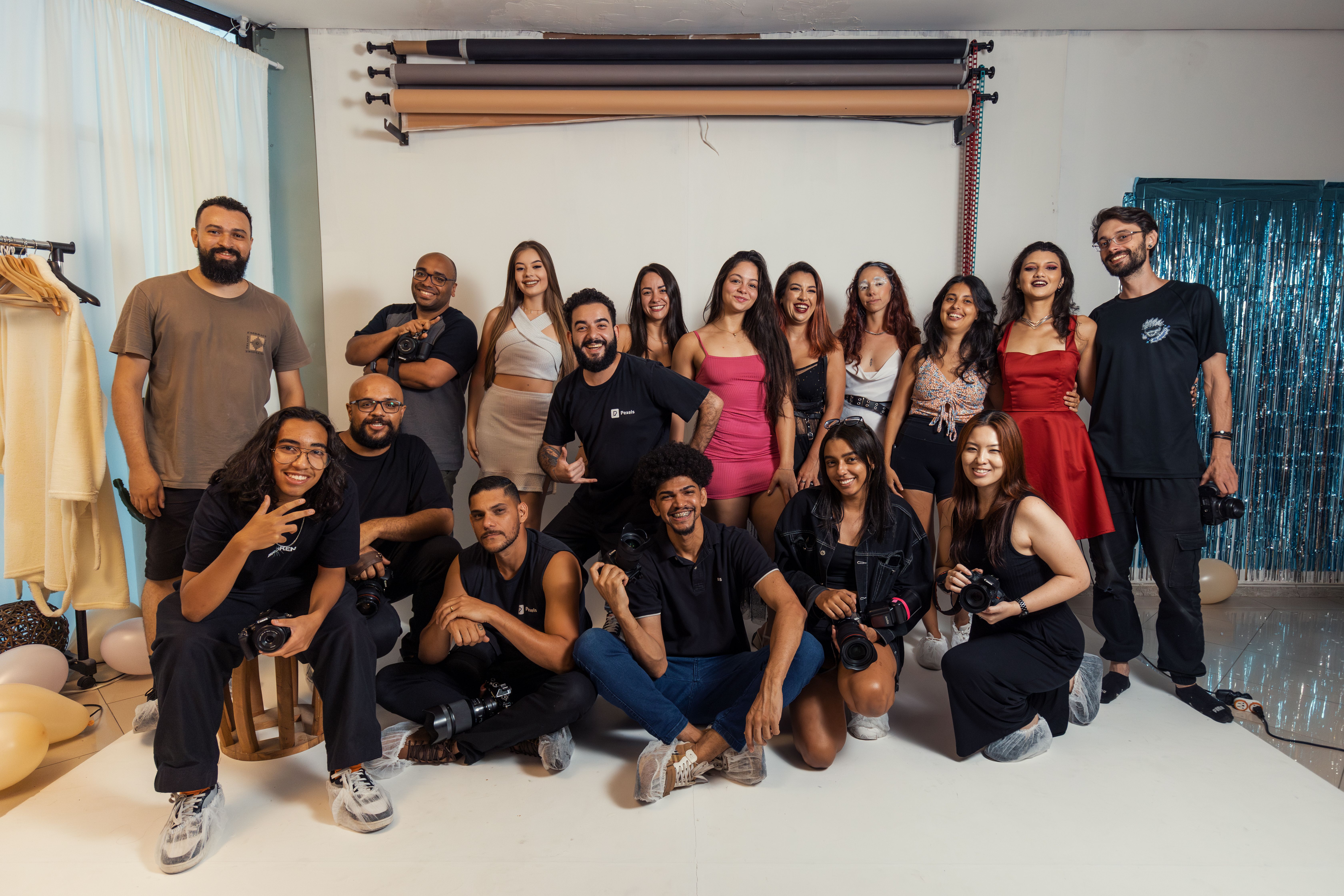 Dynamic group portrait of photographers and models celebrating together in a Brazilian studio.