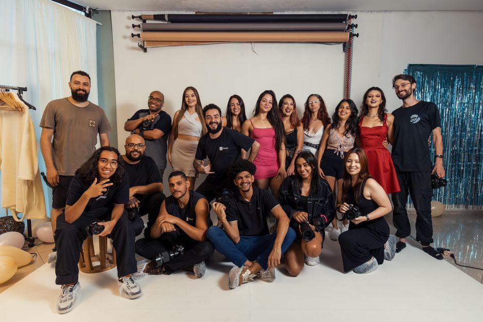 Dynamic group portrait of photographers and models celebrating together in a Brazilian studio.
