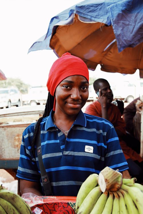 Free A woman in a striped shirt smiles at an outdoor market in Abuja, Nigeria. Stock Photo