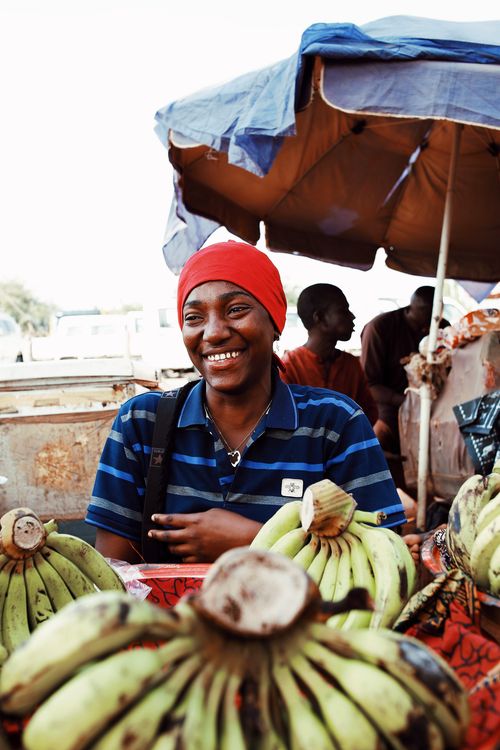 Free A cheerful street vendor in Abuja selling fresh bananas at an outdoor market. Stock Photo
