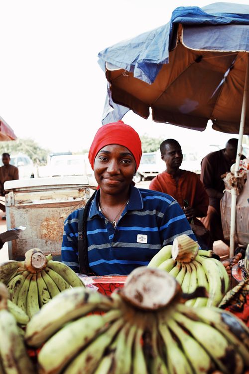 Free Portrait of a market vendor surrounded by fresh plantains at an outdoor market in Abuja, Nigeria. Stock Photo