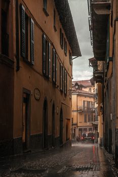 Cozy atmospheric alleyway in Como, Italy with rain-soaked streets and historic architecture.