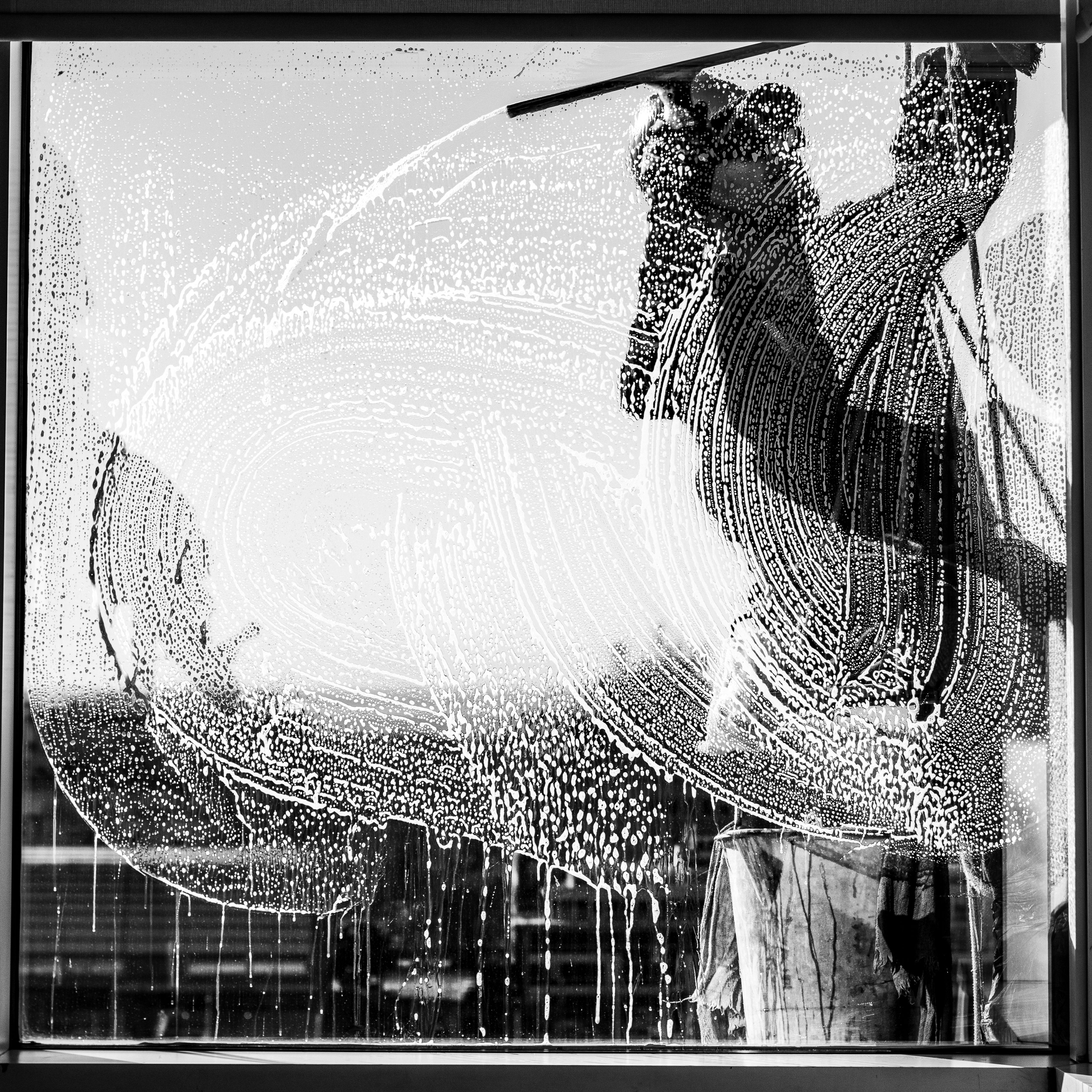 Silhouette of a worker cleaning a window in Buenos Aires, creating artistic patterns.